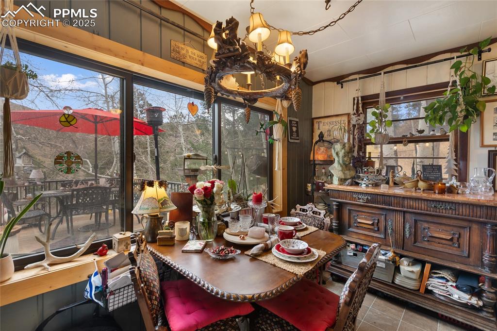 Image 22 of 47: Tiled dining area with wooden walls and a chandelier