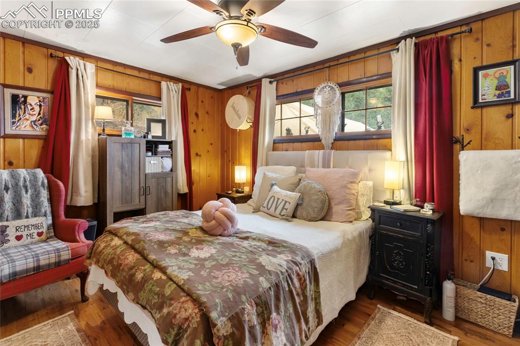 Image 24 of 47: Main Bedroom with wooden walls, wood finished floors, multiple windows, and