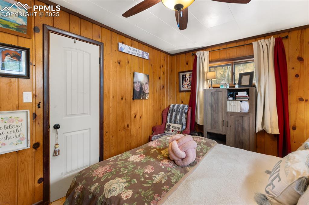 Image 25 of 47: Main Bedroom with wood walls and a ceiling fan