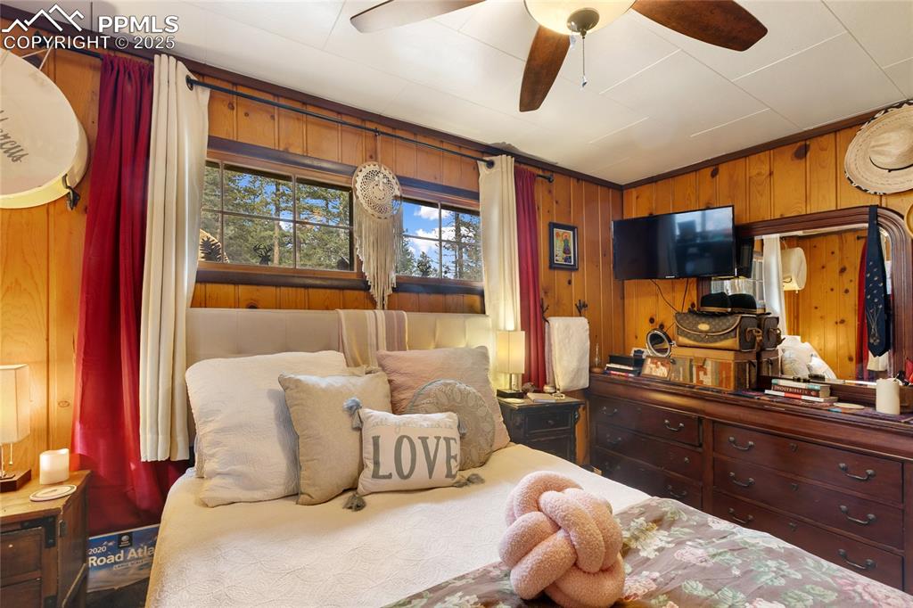 Image 26 of 47: Main Bedroom with wood walls and ceiling fan