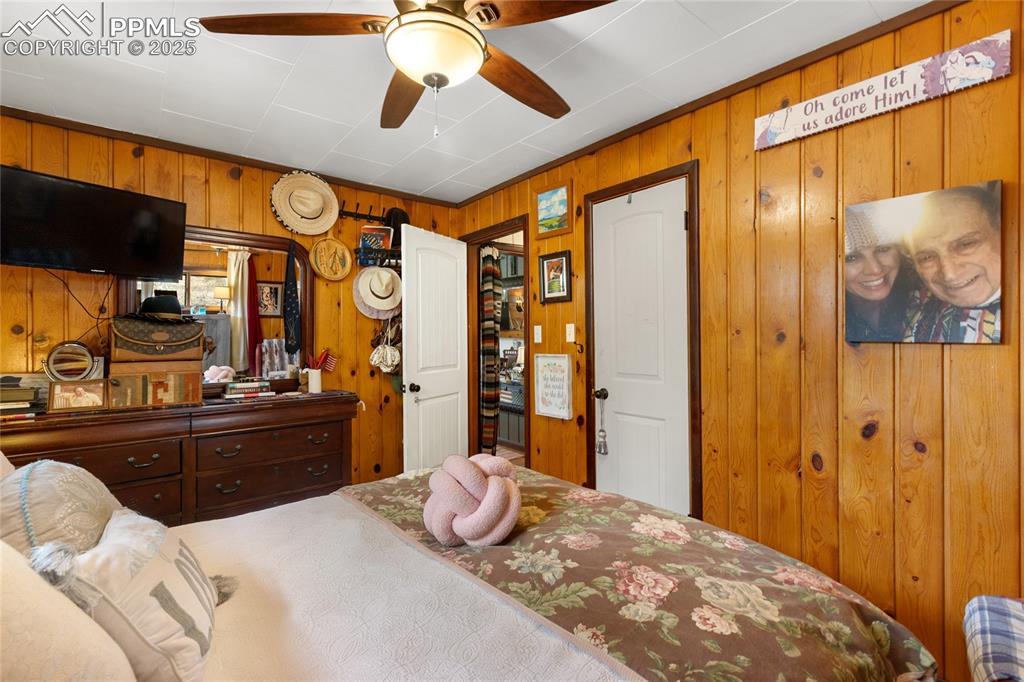 Image 27 of 47: Main Bedroom featuring wood walls and ceiling fan