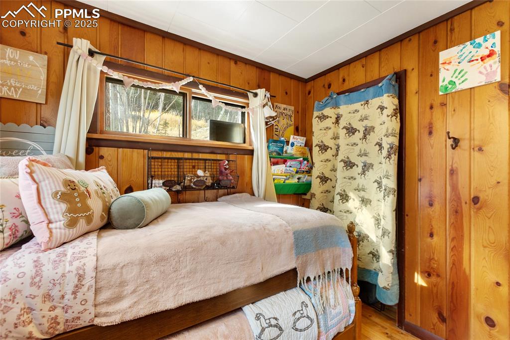 Image 28 of 47: Bedroom with wooden walls and wood finished floors