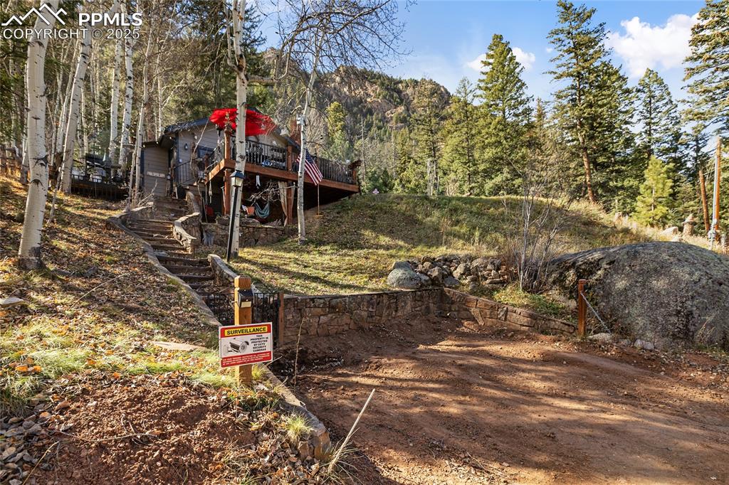 Image 38 of 47: View of yard featuring stairs, a wooded view, and a deck