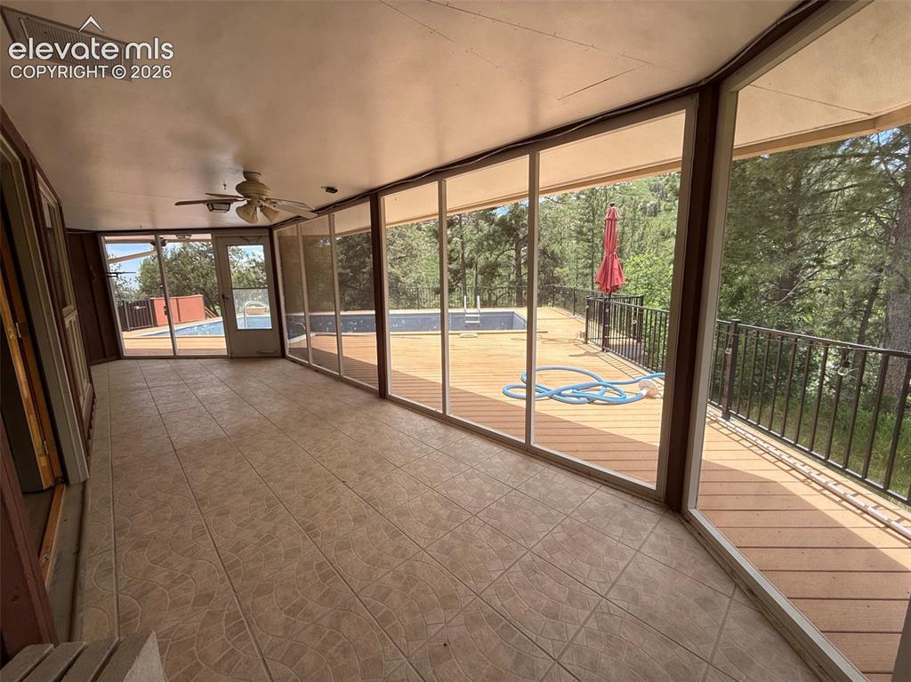 Image 14 of 33: Sunroom off living room leads to pool deck