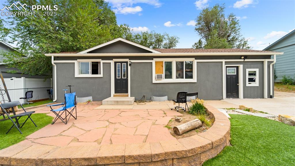 Caption: Front of house with a patio area and stucco siding