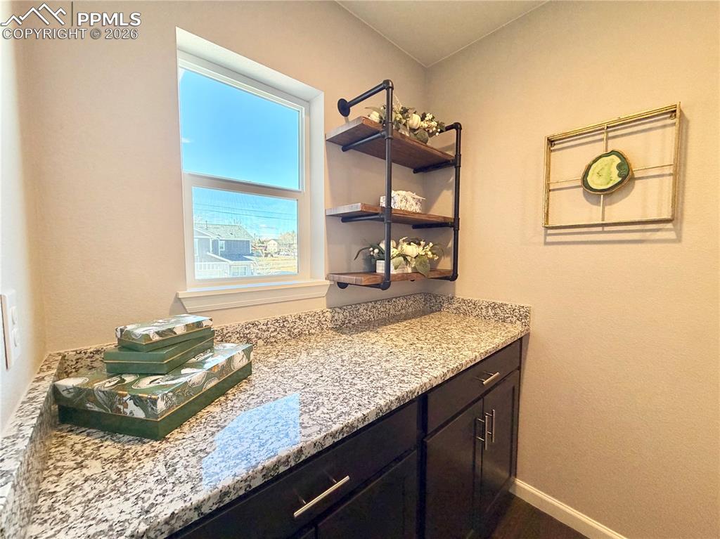 Image 22 of 41: Bar area with light stone counters and open shelves