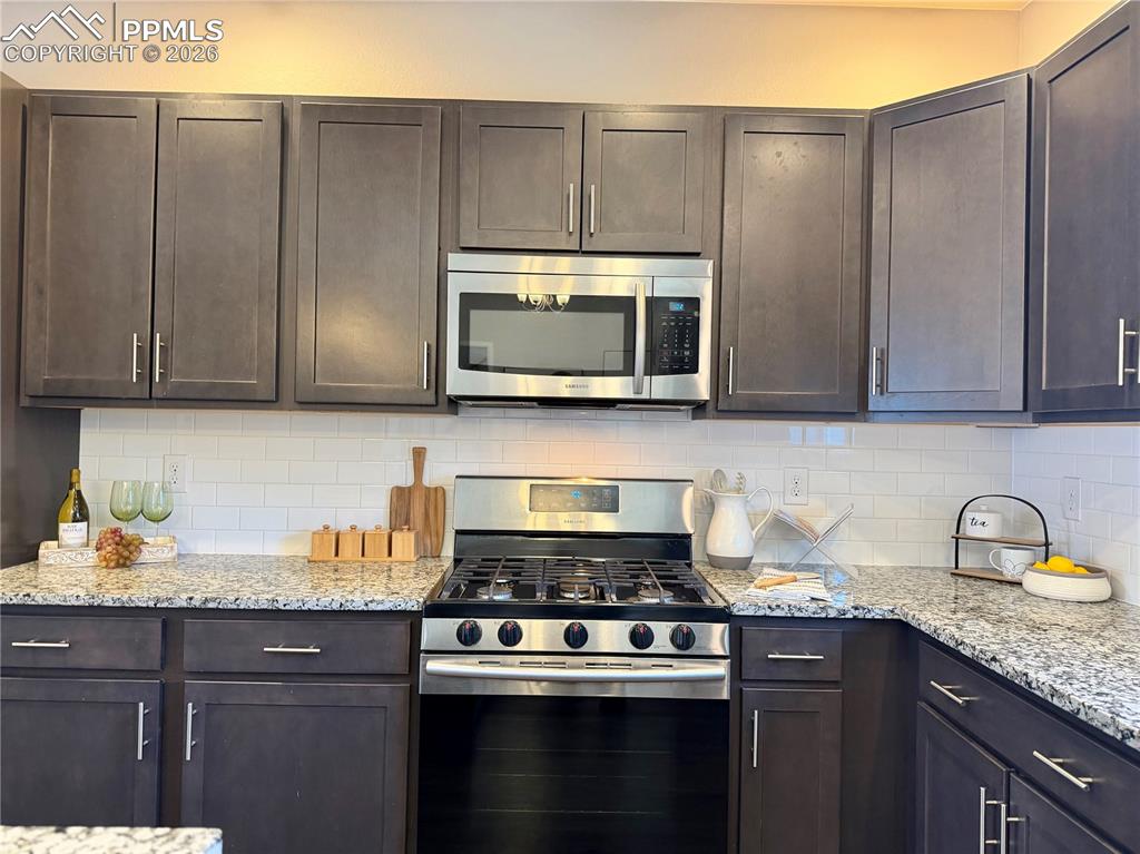 Image 9 of 41: Kitchen with appliances with stainless steel finishes, light stone counters