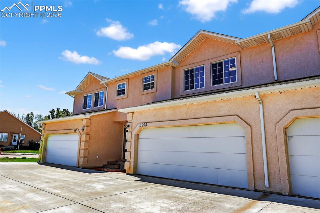Image 2 of 27: Traditional-style home featuring stucco siding, a garage, and concrete driv