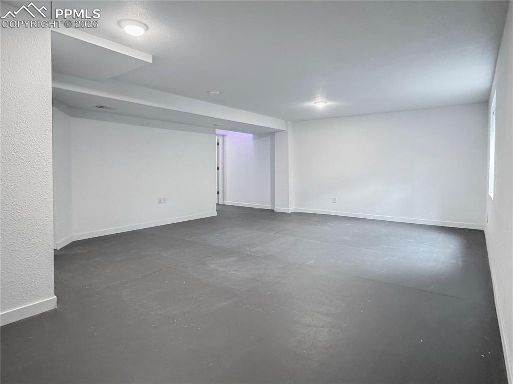 Image 20 of 27: Empty room with finished concrete flooring and baseboards