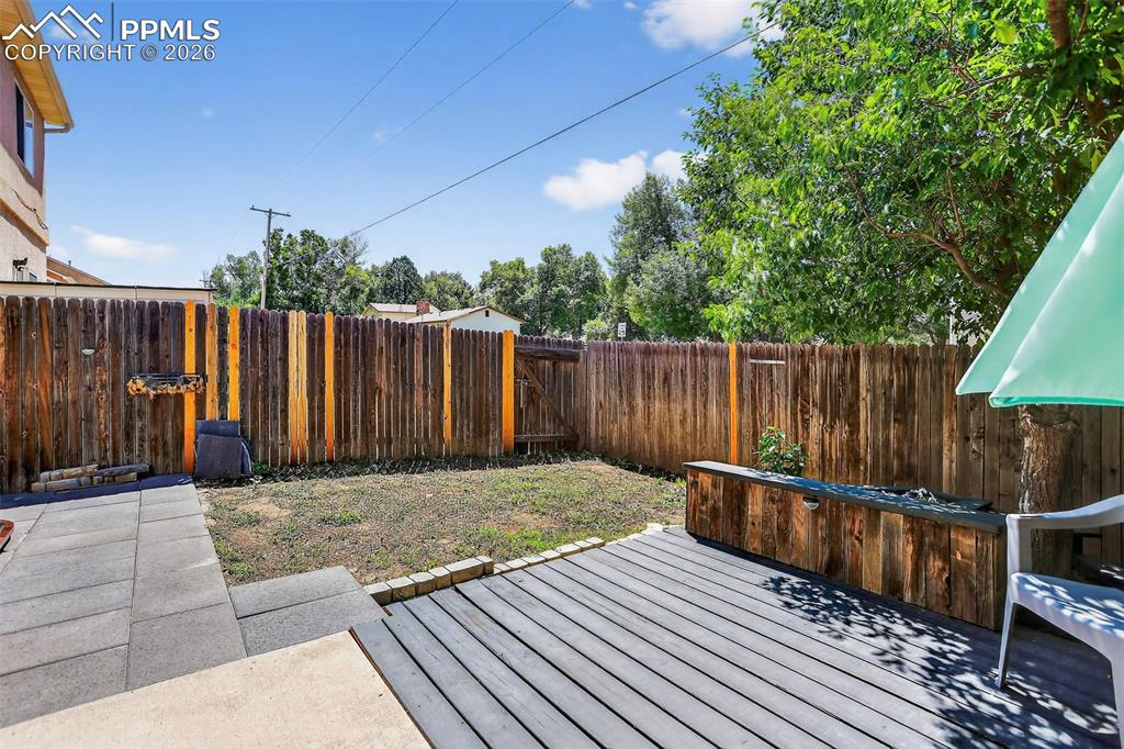 Image 25 of 27: Wooden terrace with a fenced backyard
