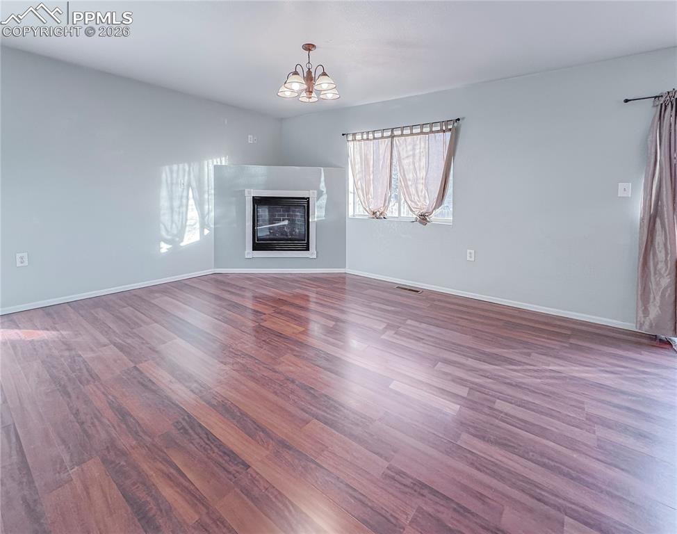 Image 5 of 27: Unfurnished living room with a glass covered fireplace, dark wood-style flo