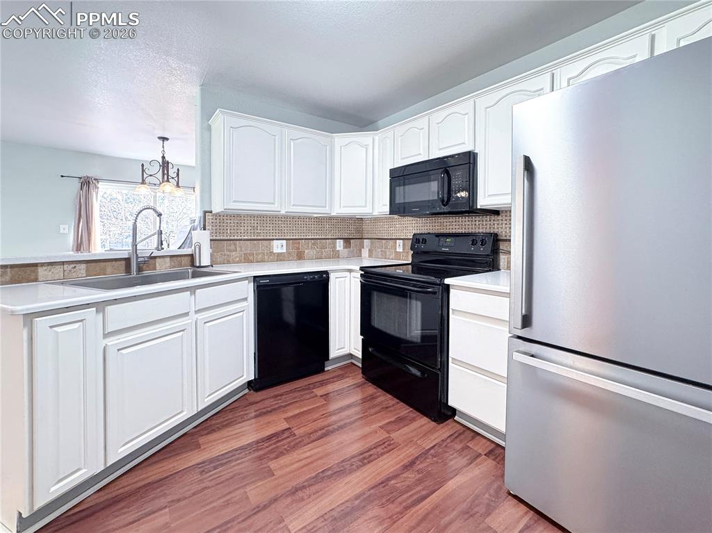 Image 7 of 27: Kitchen with black appliances, white cabinets, dark wood finished floors, b