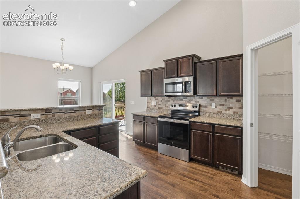 Image 11 of 46: Kitchen featuring wood-finish flooring, dark wood cabinetry, and speckled c