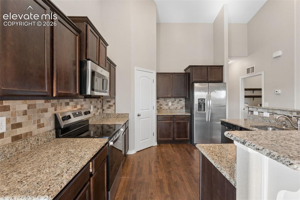 Image 14 of 46: Kitchen featuring dark wood cabinetry, stainless steel appliances, a multi-