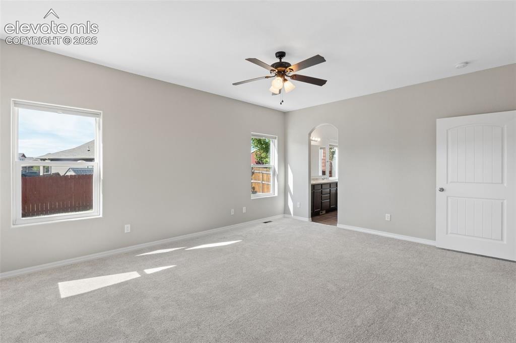 Image 16 of 46: Spacious room featuring light gray walls, plush gray carpeting, two windows