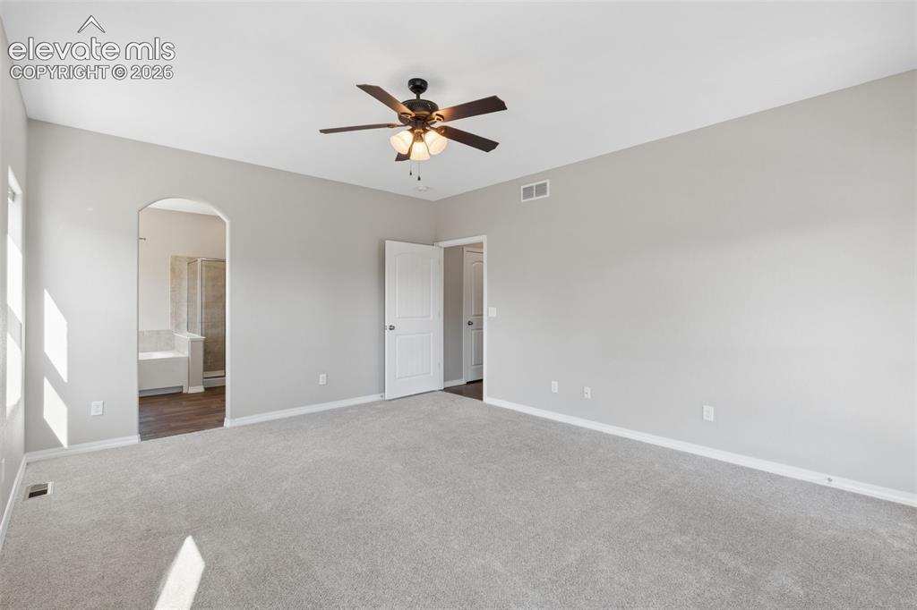 Image 18 of 46: Spacious room featuring light gray wall paint, light gray carpet, and a dar