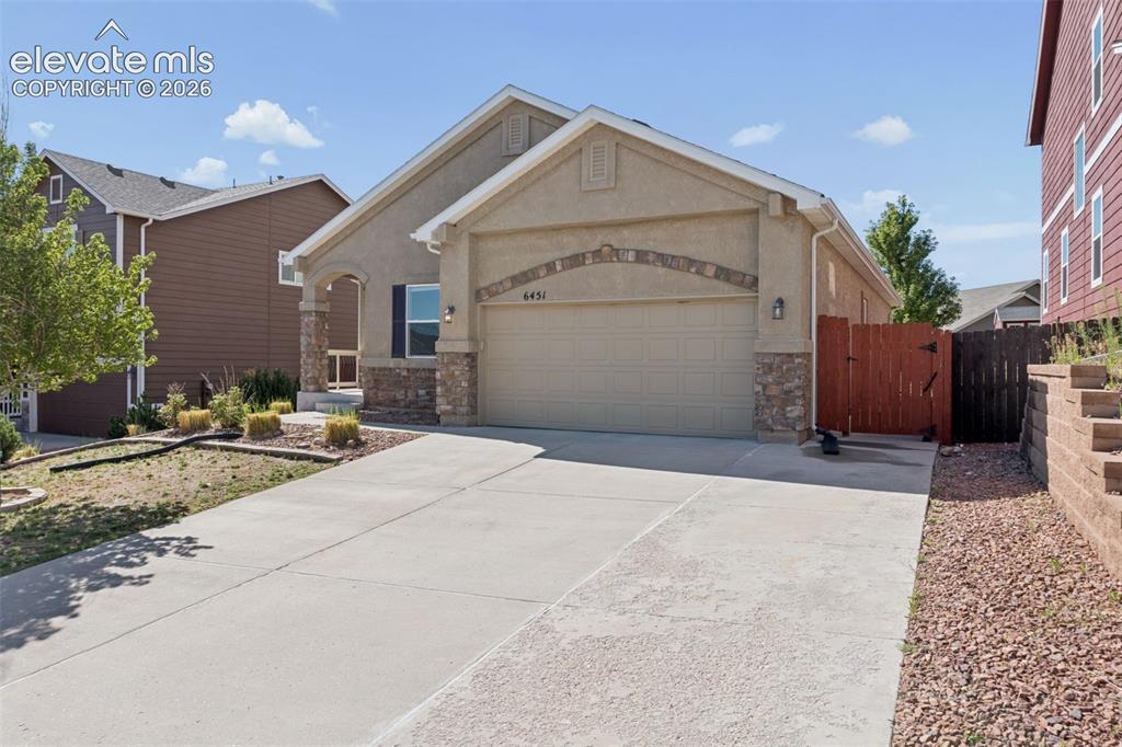 Image 2 of 46: Stucco exterior featuring a two-car garage, stone accents, and a covered en
