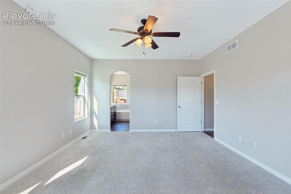 Image 20 of 46: Spacious room featuring light gray walls, plush carpeting, a ceiling fan wi