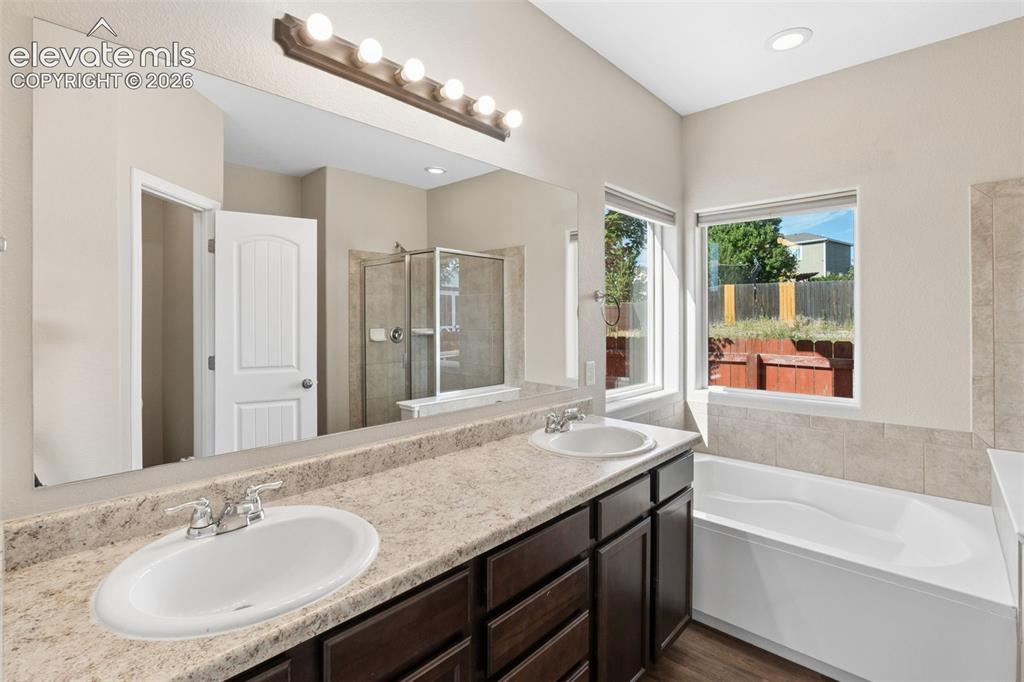 Image 21 of 46: Dual vanity with undermount sinks, speckled countertop, and dark wood-finis