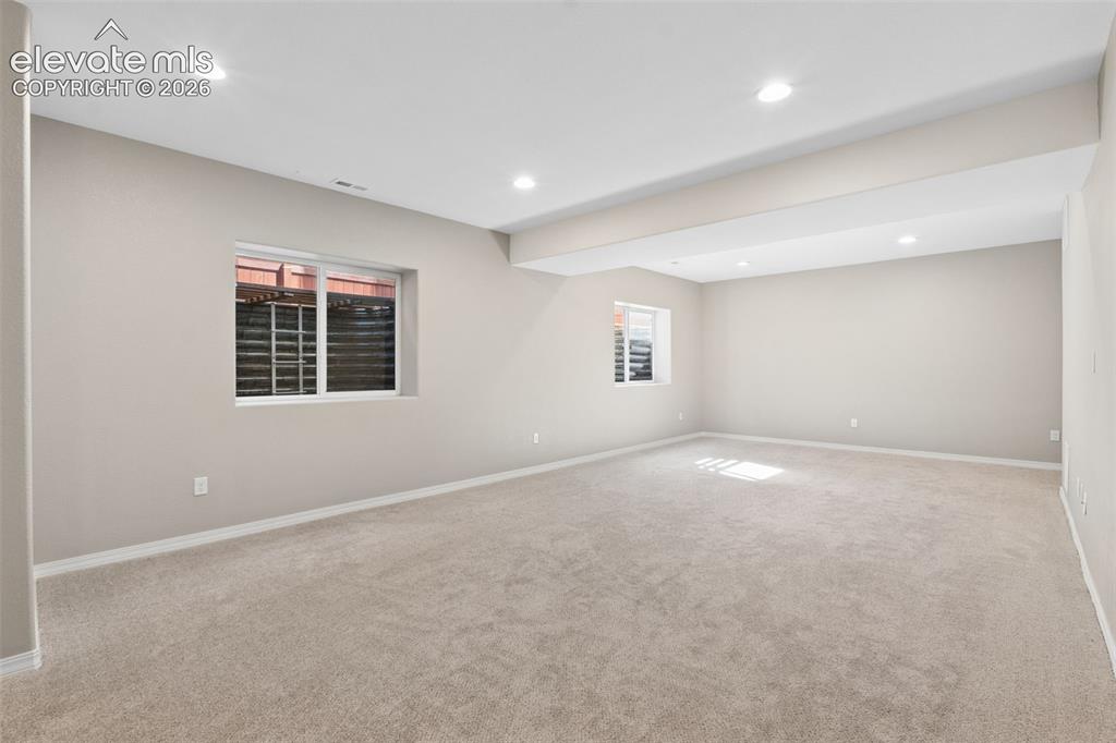 Image 28 of 46: Spacious room featuring neutral carpeting, recessed lighting, two windows,