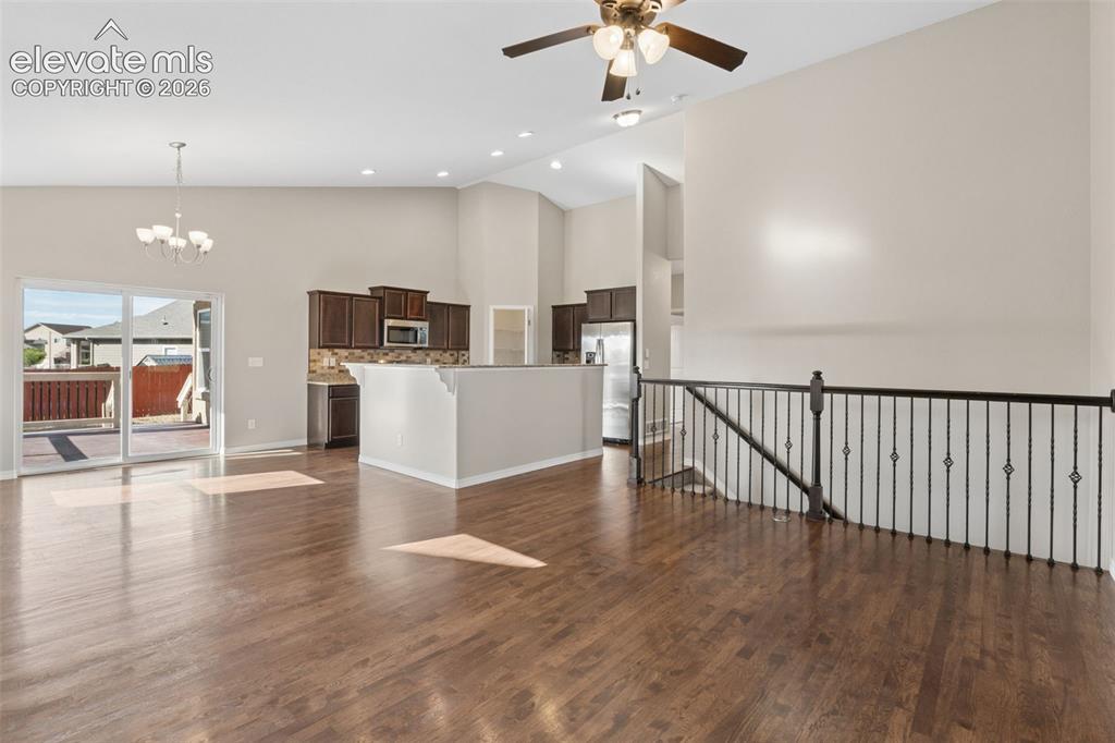 Image 3 of 46: Spacious living area featuring wood-finish flooring, a contemporary chandel