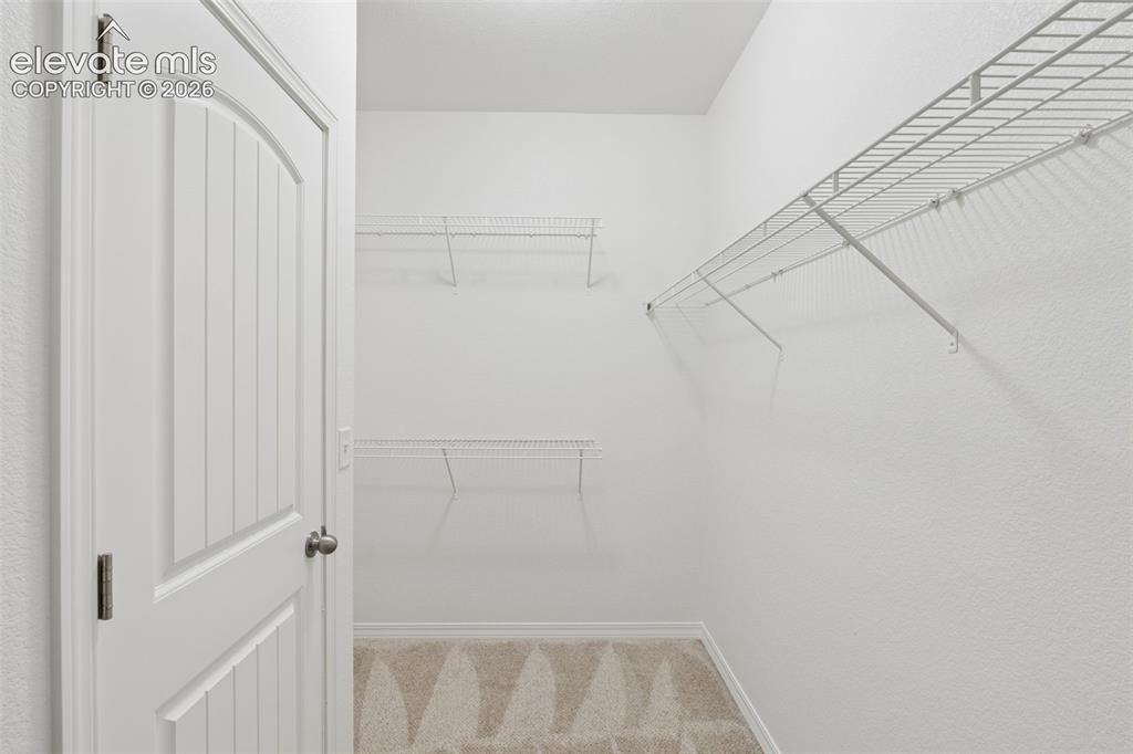 Image 40 of 46: Walk-in closet featuring white wire shelving, a white paneled door, and pat