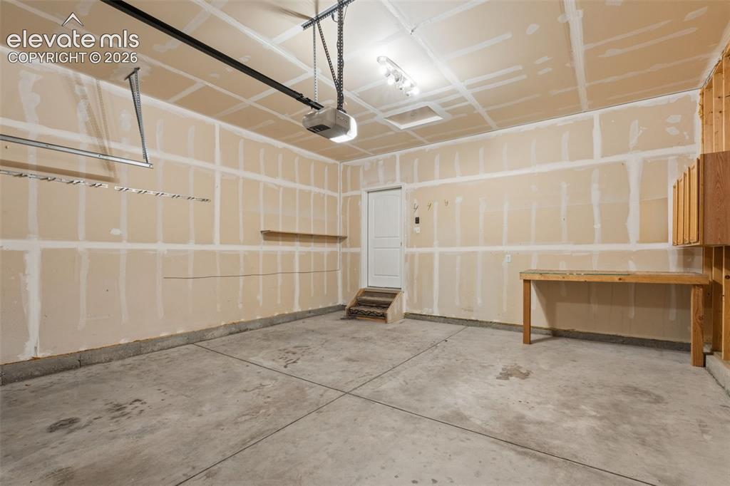 Image 43 of 46: Spacious garage with concrete flooring, exposed drywall, and overhead light