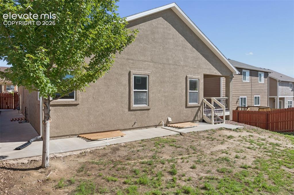 Image 45 of 46: Brown stucco exterior featuring a covered porch with white railings and sta