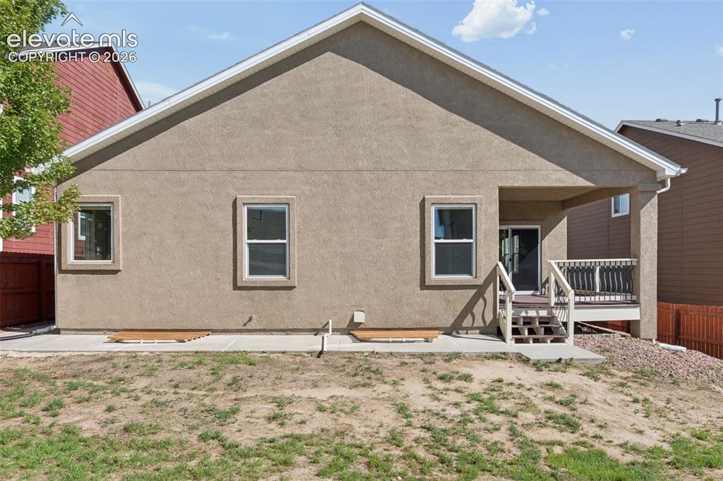 Image 46 of 46: Rear exterior featuring a covered patio, wood-finish deck, and sliding glas