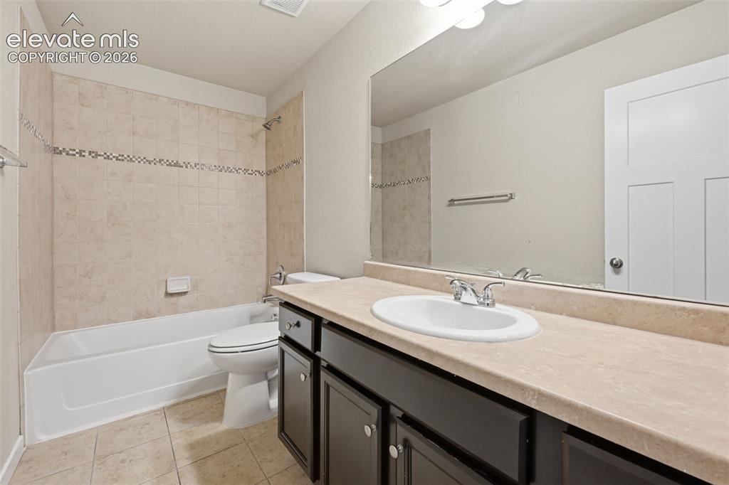 Image 38 of 43: Basement full bathroom with tiled tub-and-shower surround and generous vani