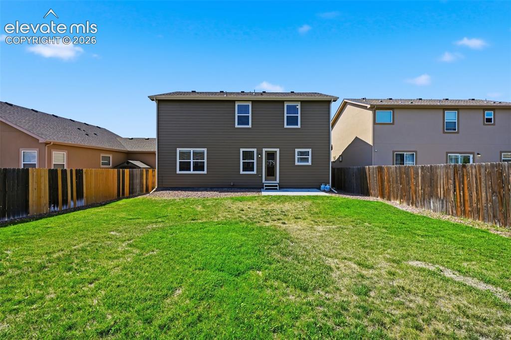 Image 39 of 43: Large fenced backyard with a patio, lawn and low-maintenance perimeter land