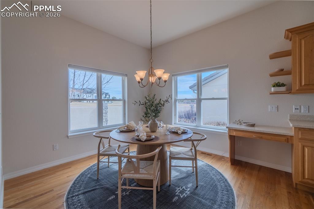 Image 14 of 50: Dining area with light wood-style floors and suspended lighting