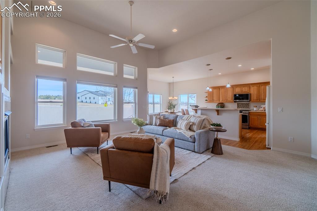 Image 18 of 50: Living room with a ceiling fan, light carpet, a high ceiling, a fireplace, 