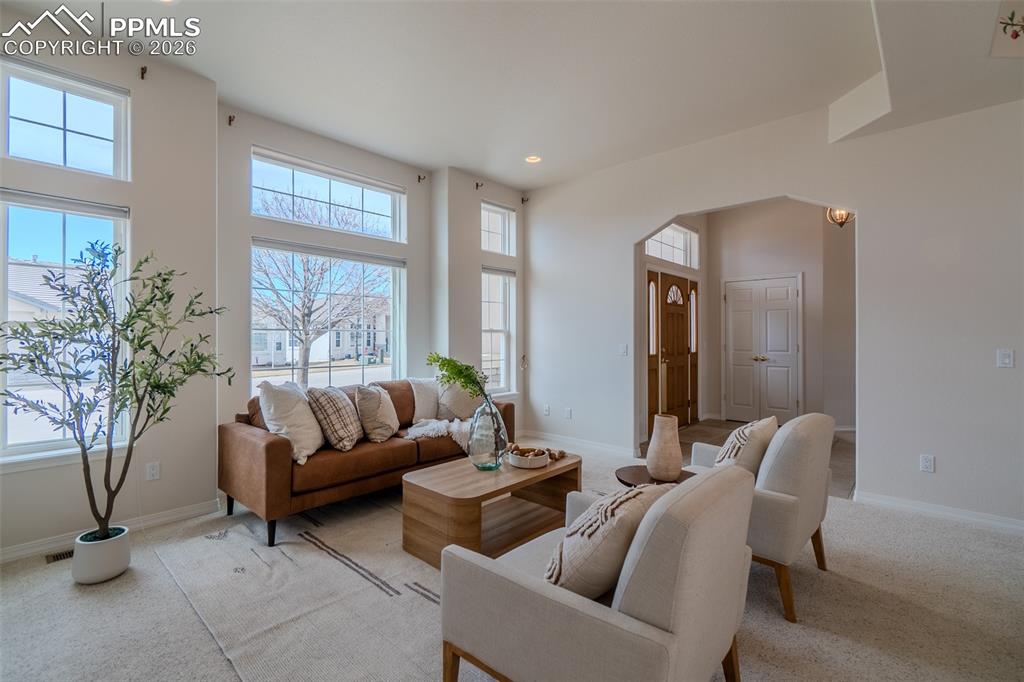 Image 2 of 50: Living area featuring arched walkways, carpet floors, and recessed lighting