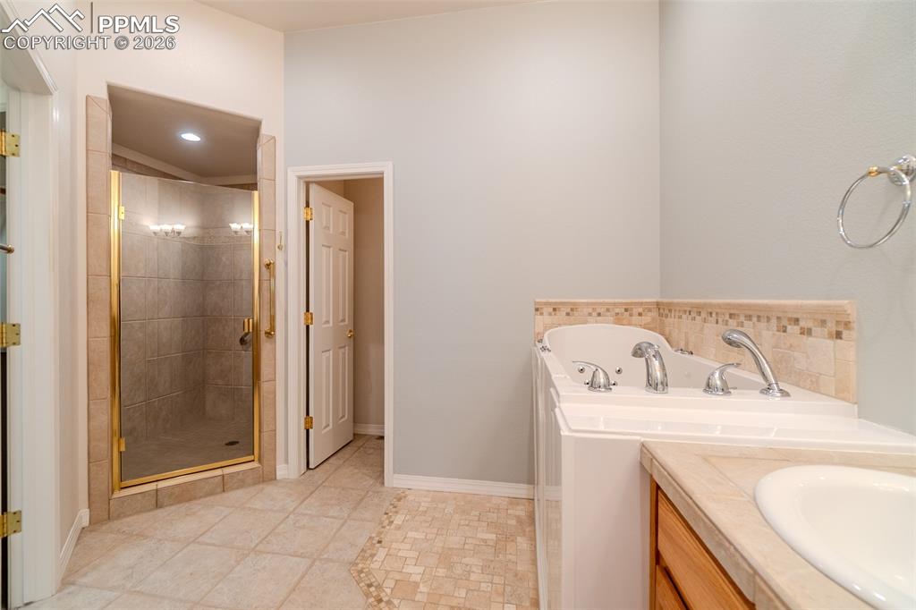 Image 24 of 50: Full bath featuring vanity, a shower stall, a bath, and light tile patterne
