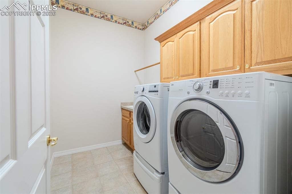 Image 28 of 50: Laundry room on Main level w/ separate washer , dryer, cabinet space and si
