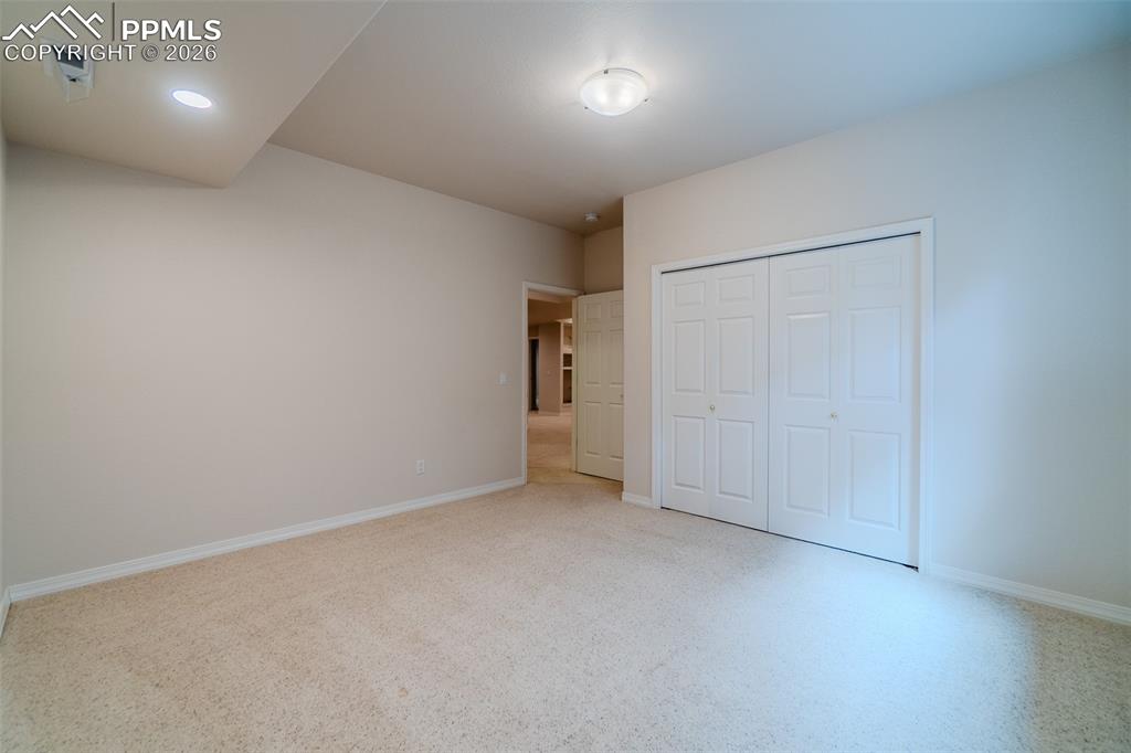Image 42 of 50: Bedroom in basement featuring light carpet and a closet