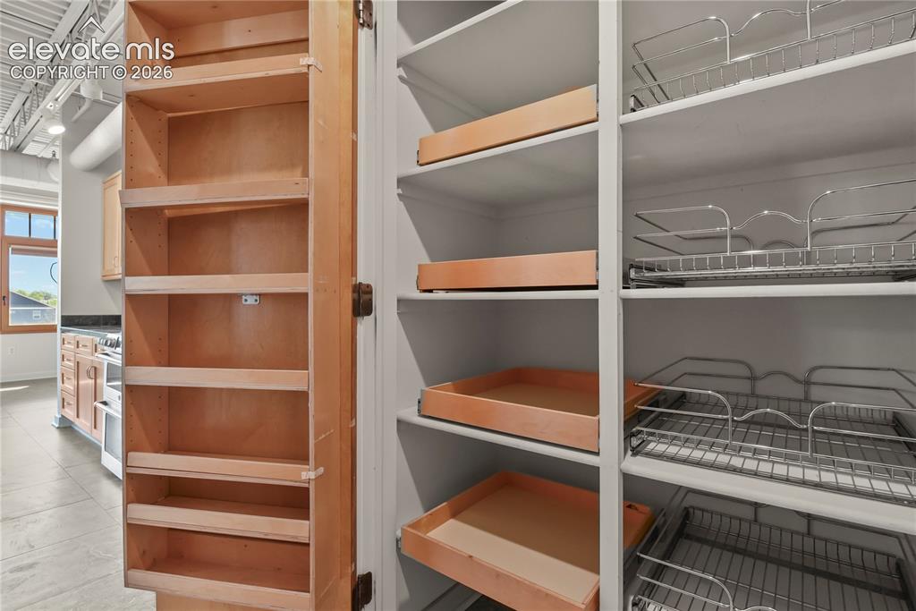 Image 8 of 50: Thoughtfully designed pantry space featuring custom pull-out shelving for e