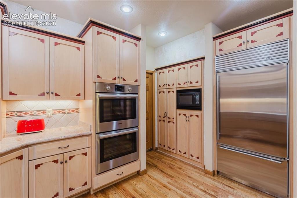 Image 15 of 50: Kitchen featuring light-toned cabinetry with decorative accents, stainless
