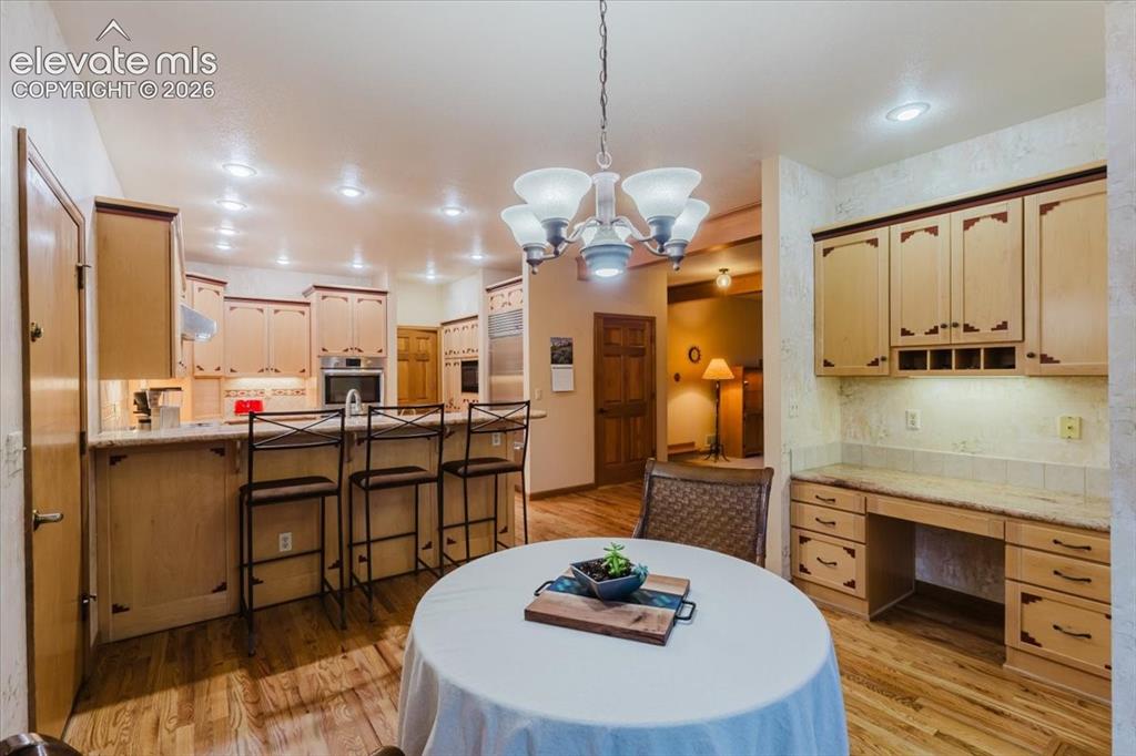 Image 16 of 50: Kitchen and dining area featuring hard wood flooring, recessed lighting, an