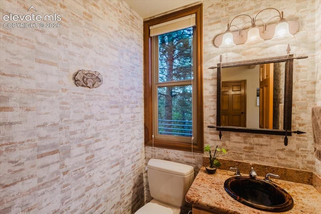 Image 17 of 50: Granite countertop vanity featuring an oval basin sink and a bronze-framed