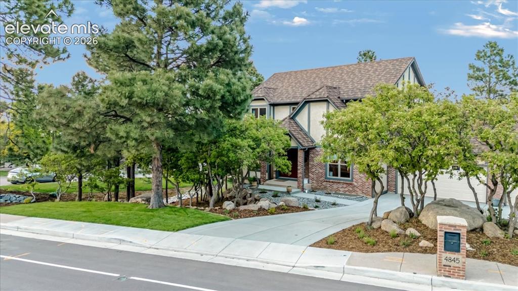 Image 2 of 50: Stately Tudor-style home featuring brick and stucco exterior, prominent gab