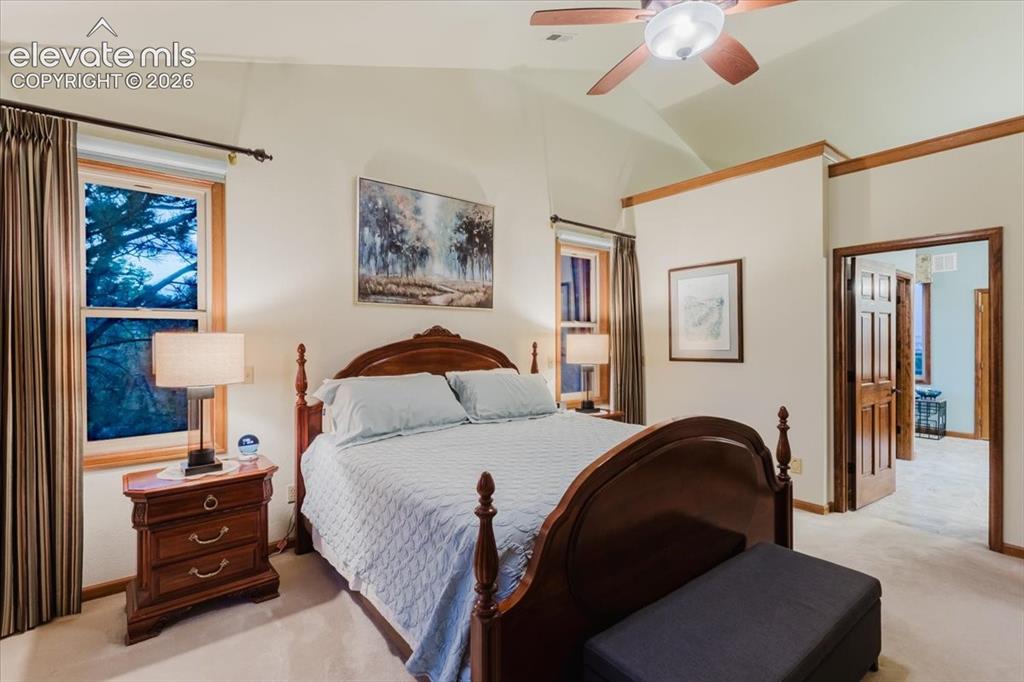Image 24 of 50: Vaulted ceiling room featuring light-toned carpeting and wood-trimmed windo