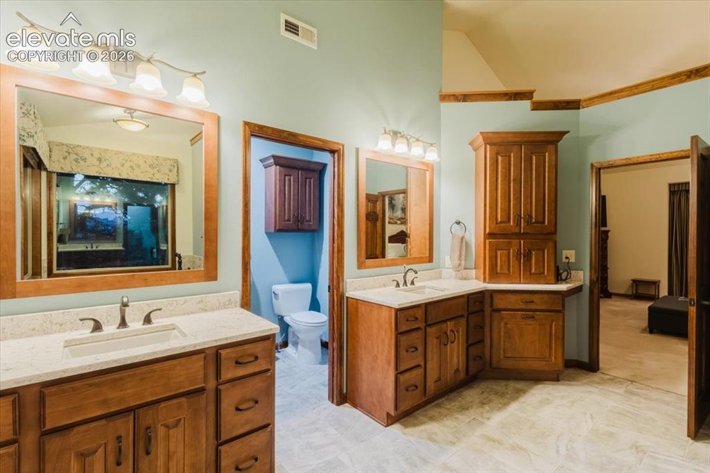 Image 26 of 50: Dual vanity featuring light-toned countertops and wood-finish cabinetry
