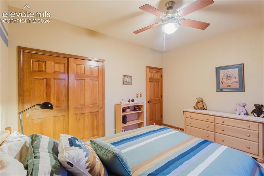 Image 27 of 50: Bedroom featuring a ceiling fan, light-toned walls, and wood-finish doors