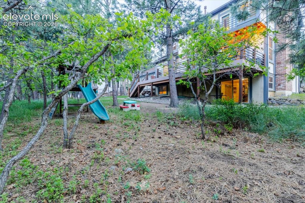 Image 39 of 50: Expansive wooded backyard featuring mature trees, a multi-level deck, and a
