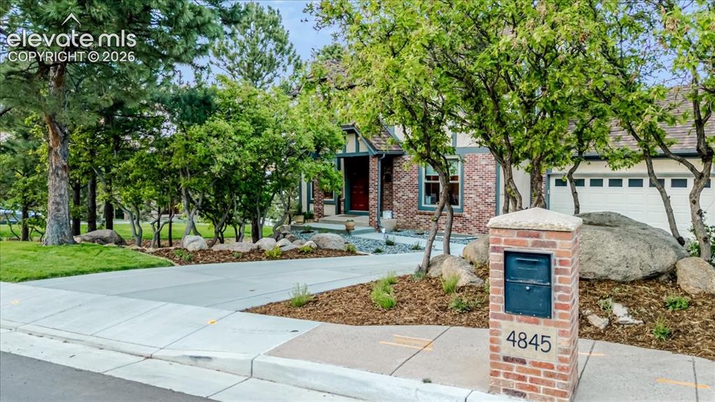 Image 41 of 50: Brick and stucco exterior with an attached garage, featuring a concrete dri