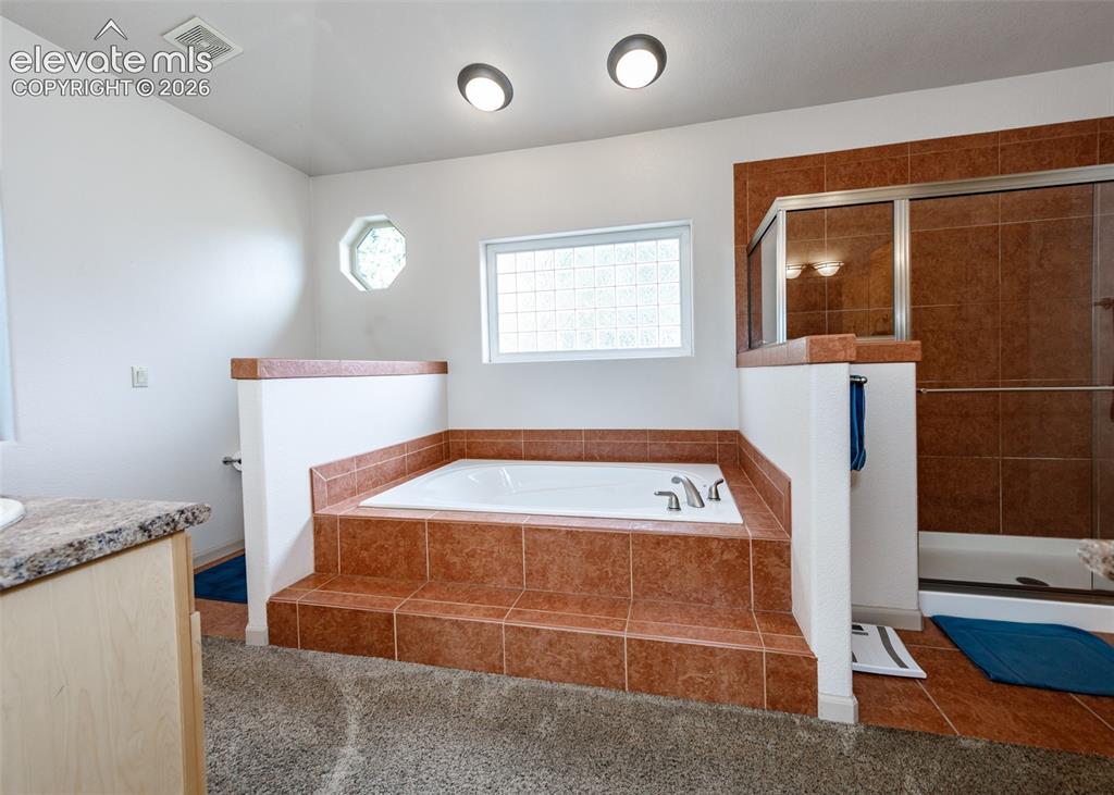 Image 14 of 43: Built-in soaking tub with tiled surround, separate shower enclosure with gl