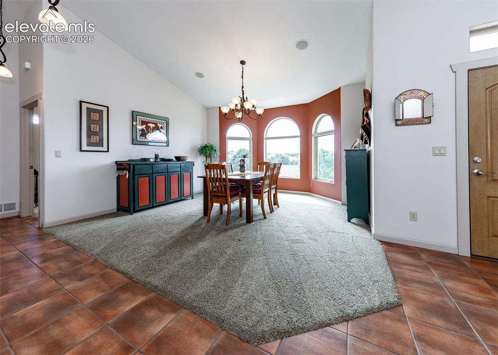 Image 21 of 50: Vaulted ceilings complement the arched windows in this open, formal dining