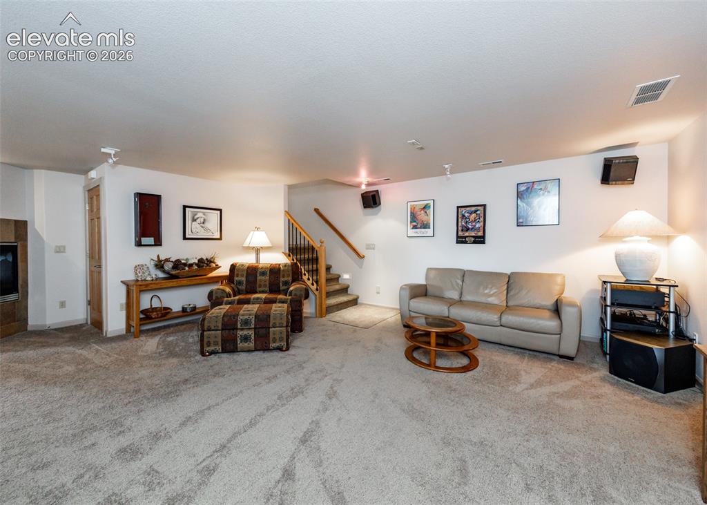 Image 30 of 43: Carpeted living area featuring track lighting, built-in wall speakers, and